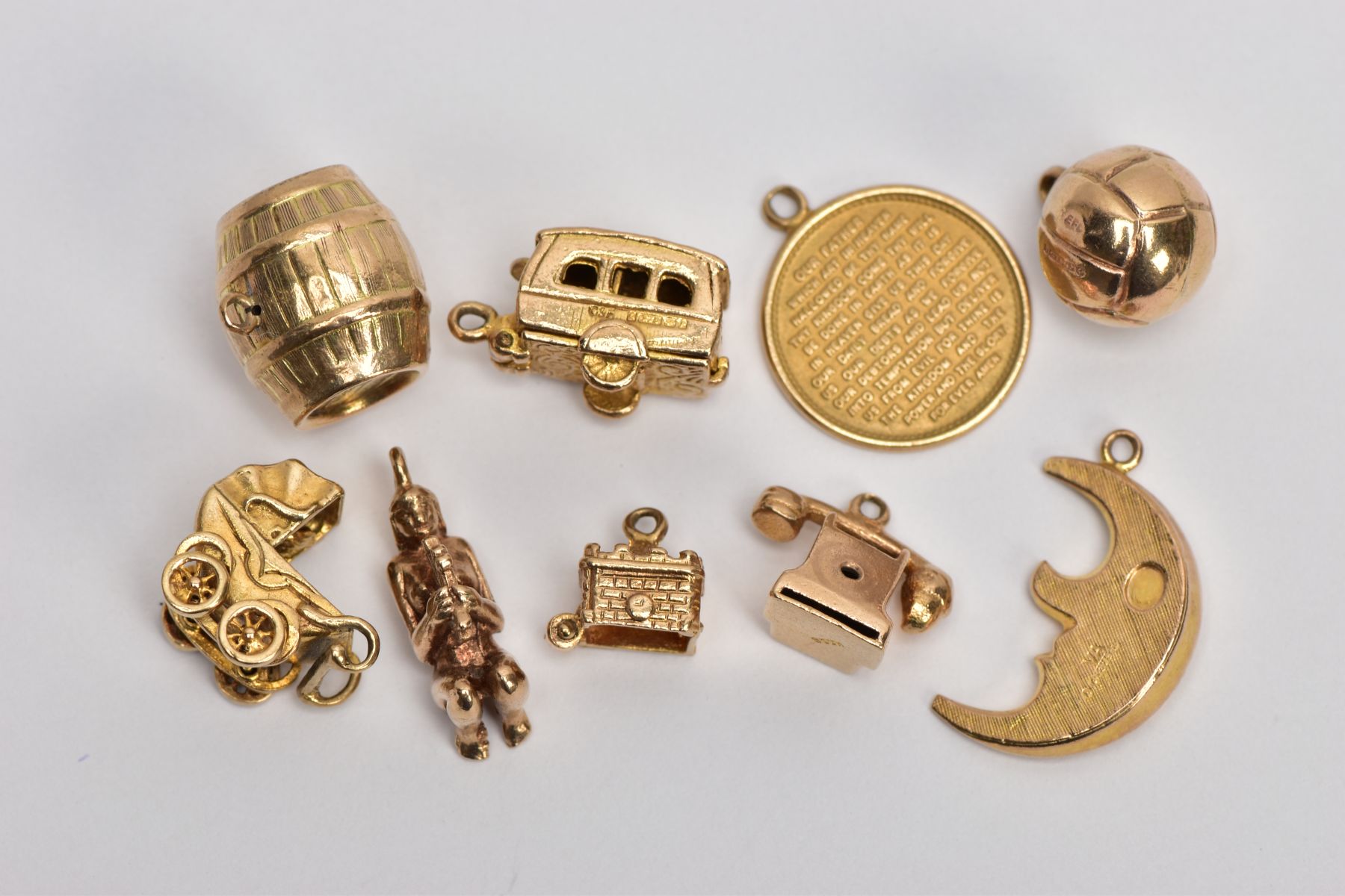 NINE 9CT GOLD CHARMS, to include a barrel, a hinged caravan, a pram and a telephone, all with 9ct