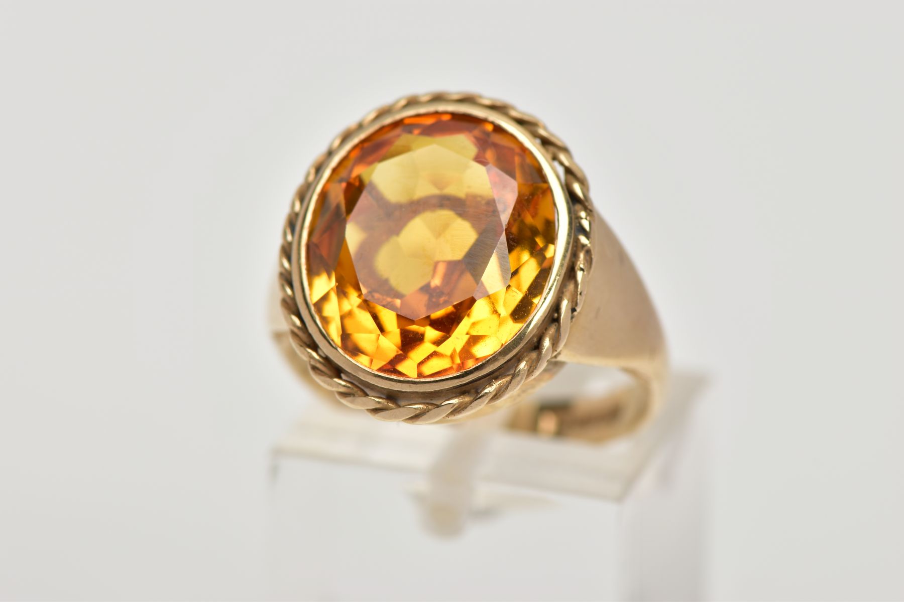 A 9CT GOLD SYNTHETIC ORANGE SAPPHIRE DRESS RING, designed with a large oval cut synthetic orange