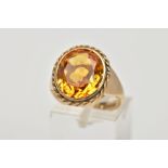 A 9CT GOLD SYNTHETIC ORANGE SAPPHIRE DRESS RING, designed with a large oval cut synthetic orange