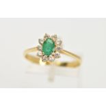 A YELLOW METAL EMERALD AND CUBIC ZIRCONIA CLUSTER RING, centring on a claw set, oval cut emerald,