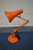 AN ORANGE ANGLE POISE DESK LAMP