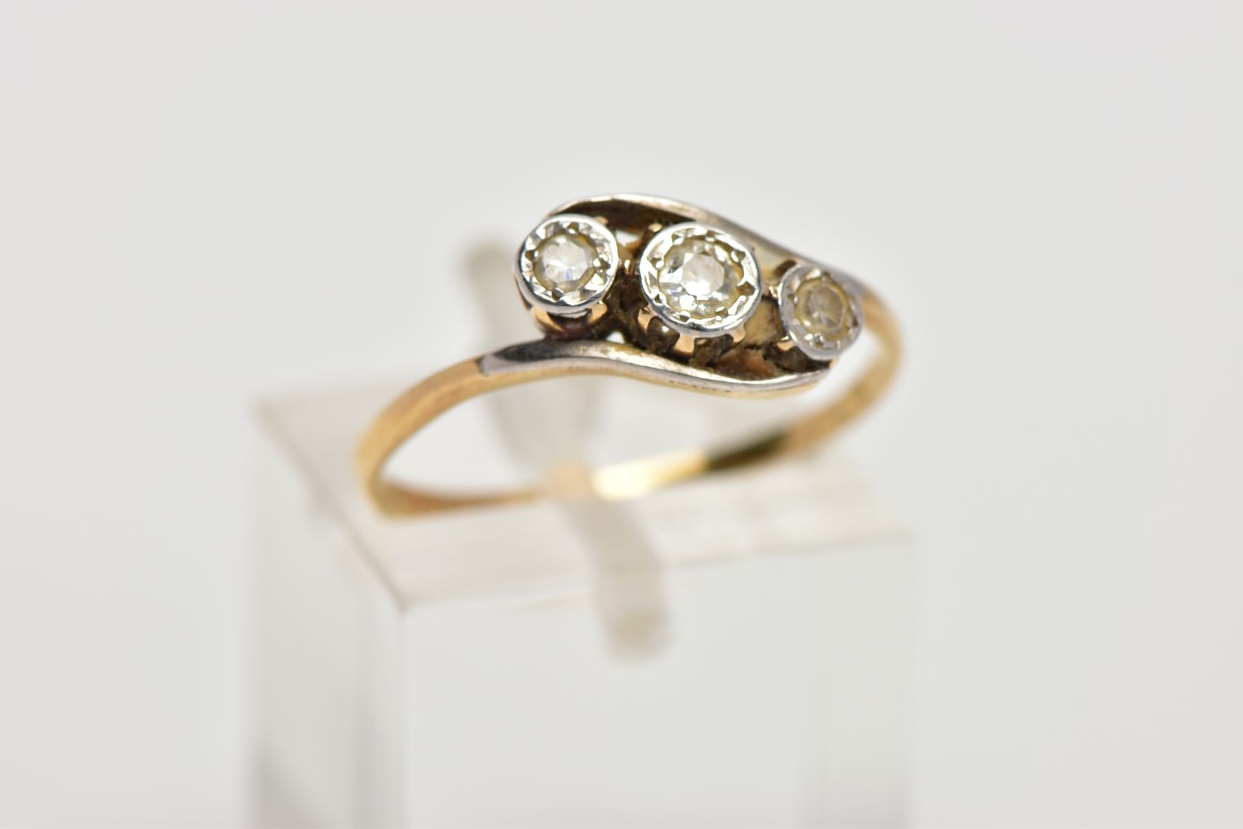 A YELLOW METAL, THREE STONE DIAMOND RING, of a crossover design, set with three illusion set round - Image 4 of 4