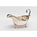 AN EARLY 20TH CENTURY SILVER GRAVY BOAT, with gadrooned top edge, scrolling handle and three feet,