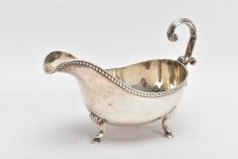 AN EARLY 20TH CENTURY SILVER GRAVY BOAT, with gadrooned top edge, scrolling handle and three feet,