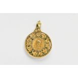 A YELLOW METAL PENDANT, of a circular form depicting the virgin Mary within a surround of vine