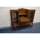 AN EARLY 20TH CENTURY OAK SIDE BY SIDE BUREAU/BOOKCASE, a raised back with centre pediment above a