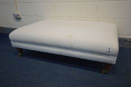 A LARGE MODERN POUFFE in cream, turned legs on brass casters, width 117cm x depth 77cm x height