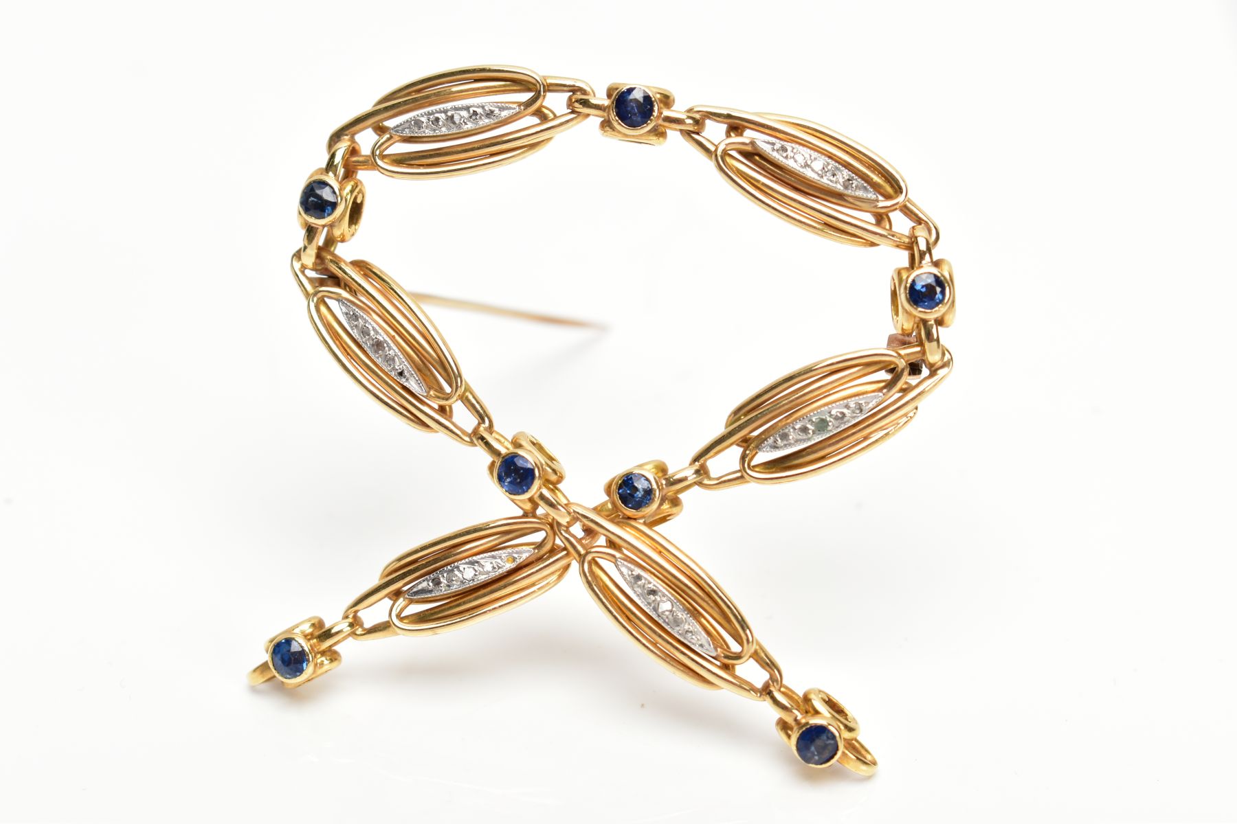 A YELLOW METAL SAPPHIRE AND DIAMOND SET BROOCH, openwork cross over design, set with circular cut