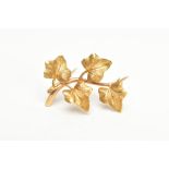 A YELLOW METAL VINE LEAF BROOCH, textured vine leaves on a plain polished stem, fitted with a brooch