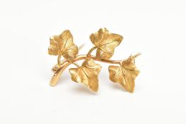 A YELLOW METAL VINE LEAF BROOCH, textured vine leaves on a plain polished stem, fitted with a brooch