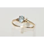 A YELLOW METAL TOPAZ RING, designed with a claw set, oval cut blue topaz, detailed shoulders,