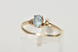 A YELLOW METAL TOPAZ RING, designed with a claw set, oval cut blue topaz, detailed shoulders,