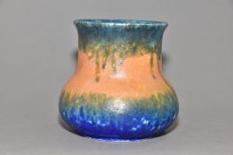 RUSKIN POTTERY, an elephant's foot shaped vase, covered in bands of green, orange and blue glazes,