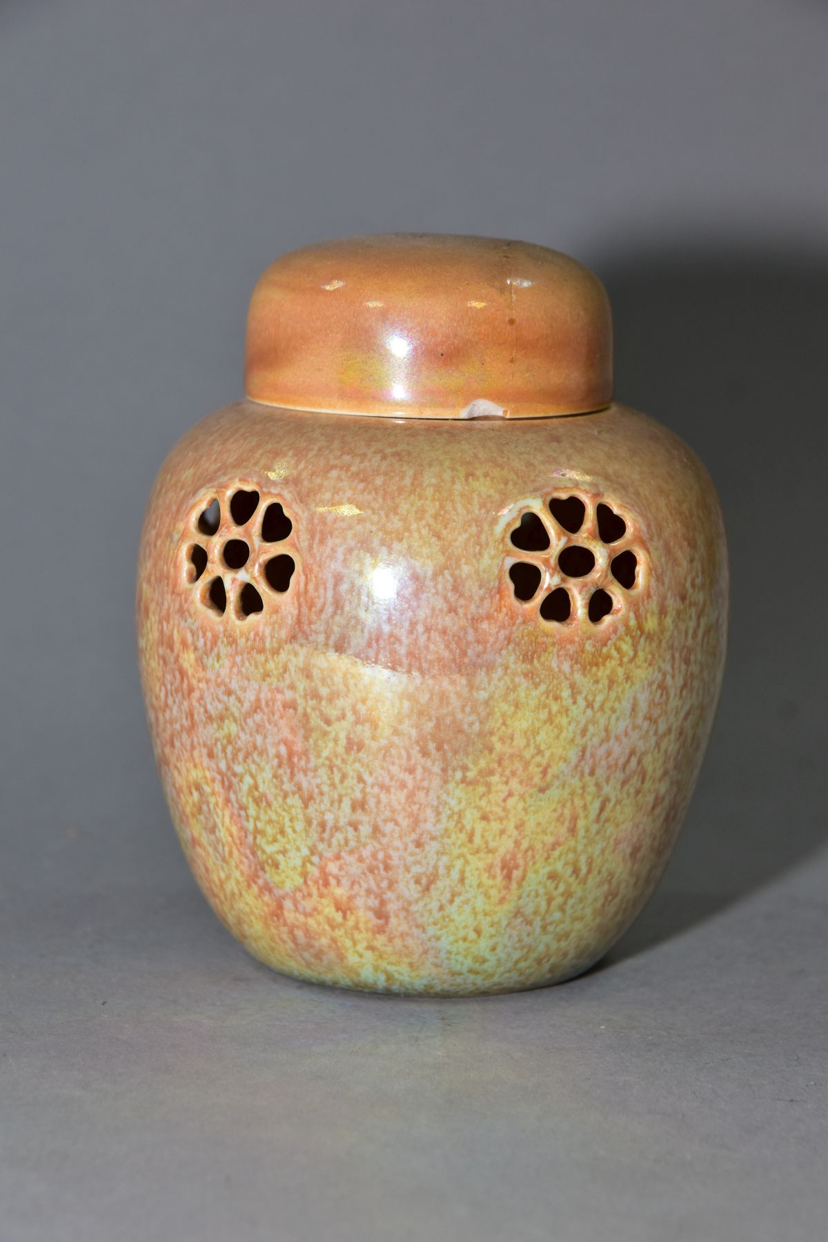 RUSKIN POTTERY, a peach lustre reticulated ginger/pot pourri jar with cover, the body pierced with