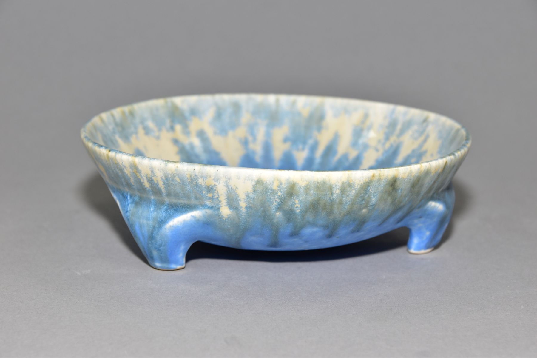 RUSKIN POTTERY, a shallow bowl raised on three feet, blue and orange crystalline glaze over white