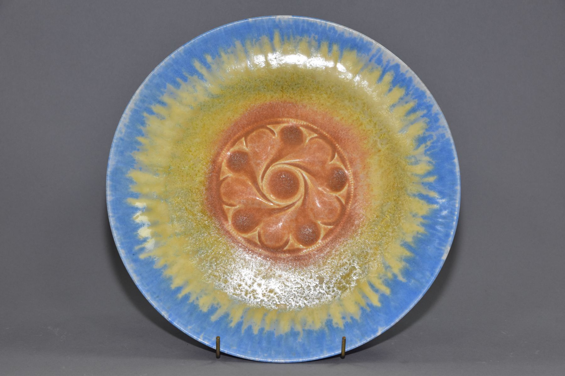 RUSKIN POTTERY, a circular wall plaque/plate, having a central embossed section, the whole covered