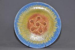 RUSKIN POTTERY, a circular wall plaque/plate, having a central embossed section, the whole covered