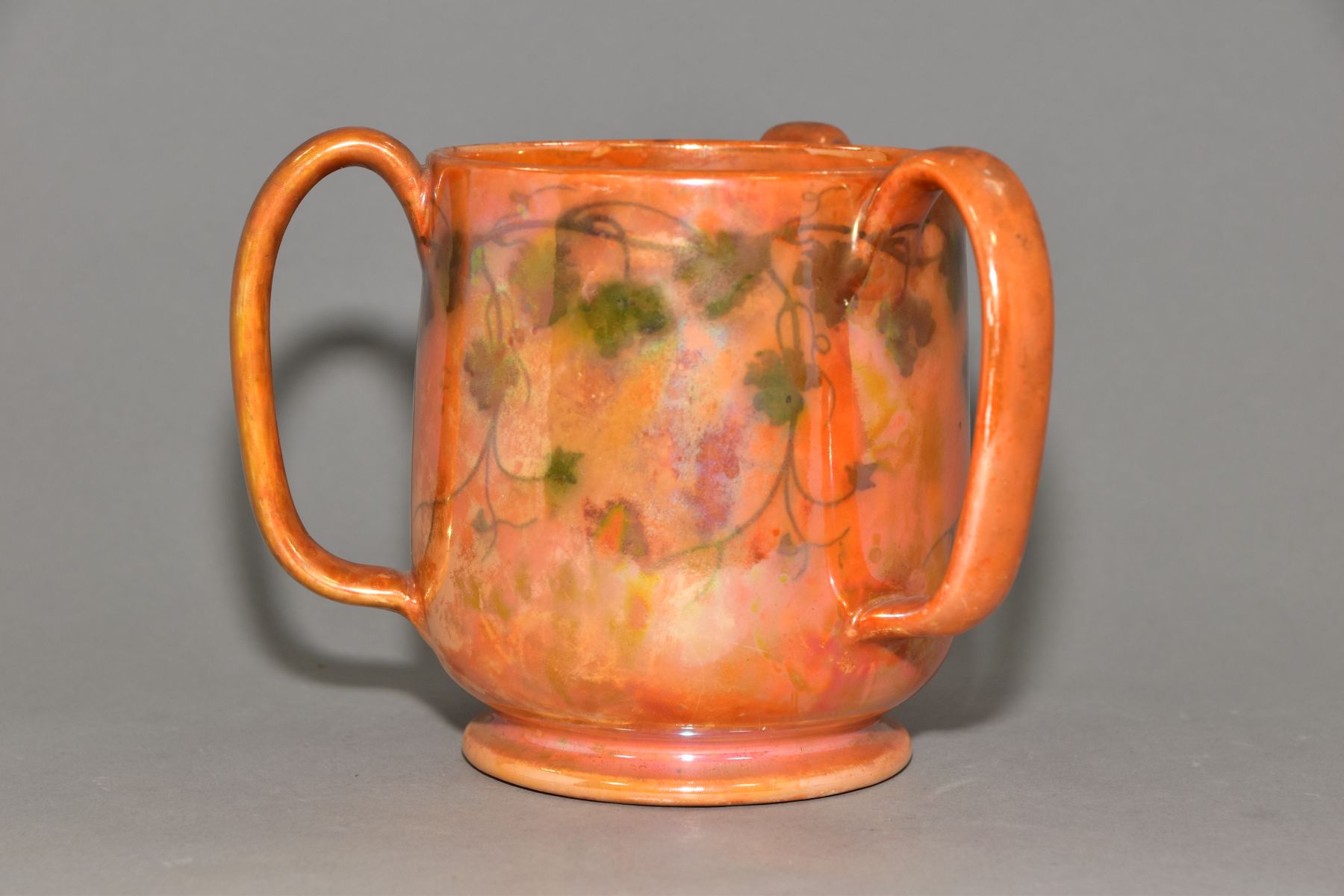 RUSKIN POTTERY, a three handled tyg decorated in orange lustre with a band of underglazed foliate