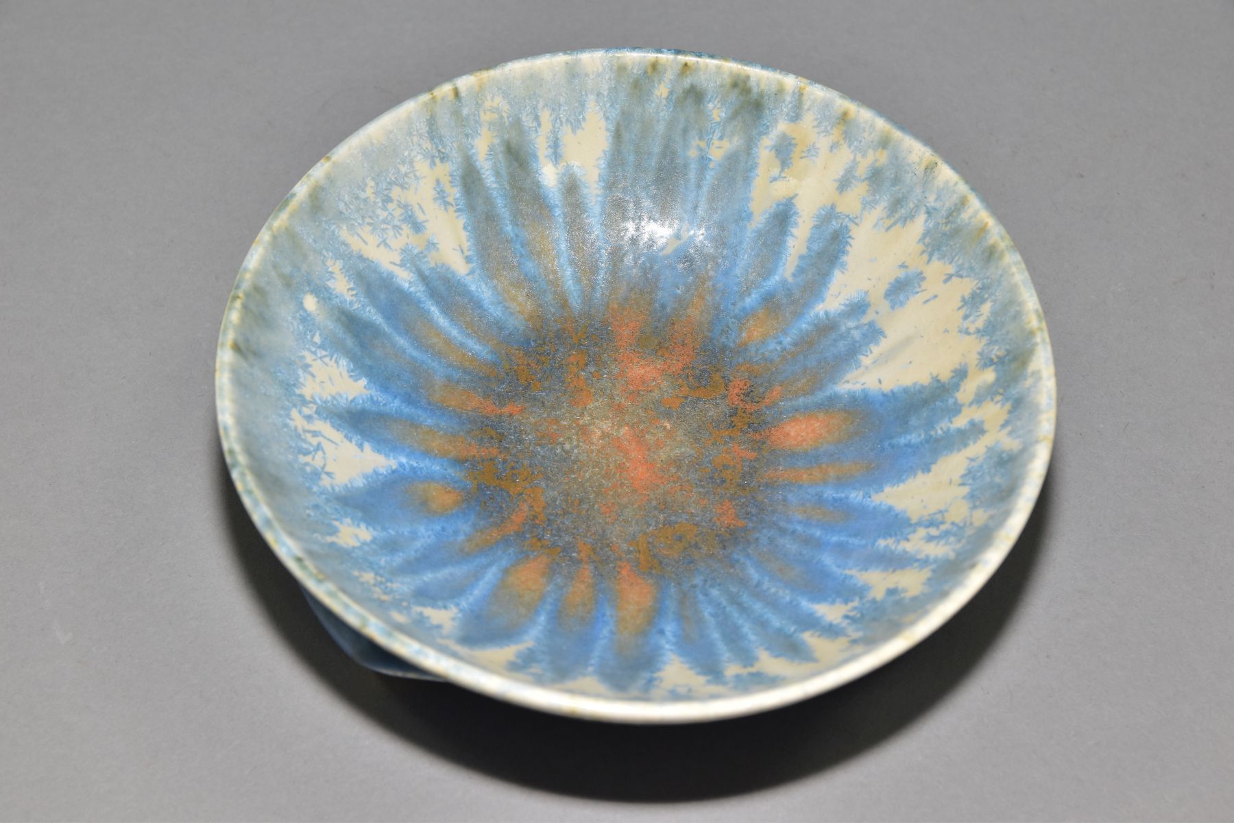 RUSKIN POTTERY, a shallow bowl raised on three feet, blue and orange crystalline glaze over white - Image 3 of 4