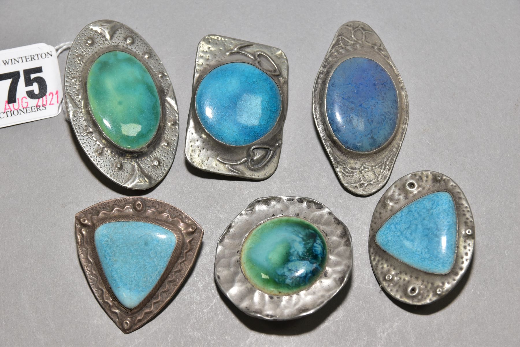 SIX RUSKIN STYLE BROOCHES, five enamels set into pewter, one stamped FTG hand wrought, one enamel