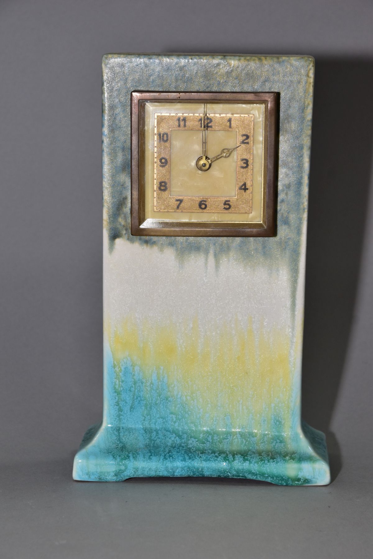 RUSKIN POTTERY, a rectangular clock case with flared base, matt green fading to white and yellow,