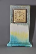 RUSKIN POTTERY, a rectangular clock case with flared base, matt green fading to white and yellow,