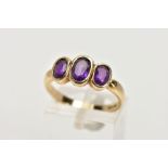 A 9CT GOLD THREE STONE AMETHYST RING, the three graduated oval amethysts within collet settings to