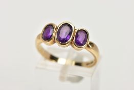 A 9CT GOLD THREE STONE AMETHYST RING, the three graduated oval amethysts within collet settings to