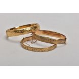 THREE ROLLED GOLD HINGED BANGLES, each decorated with an engraved foliate design, fitted with push