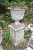 A COMPOSITE GARDEN URN ON A SQUARE COLUMN BASE with two section top showing foliate detailing and