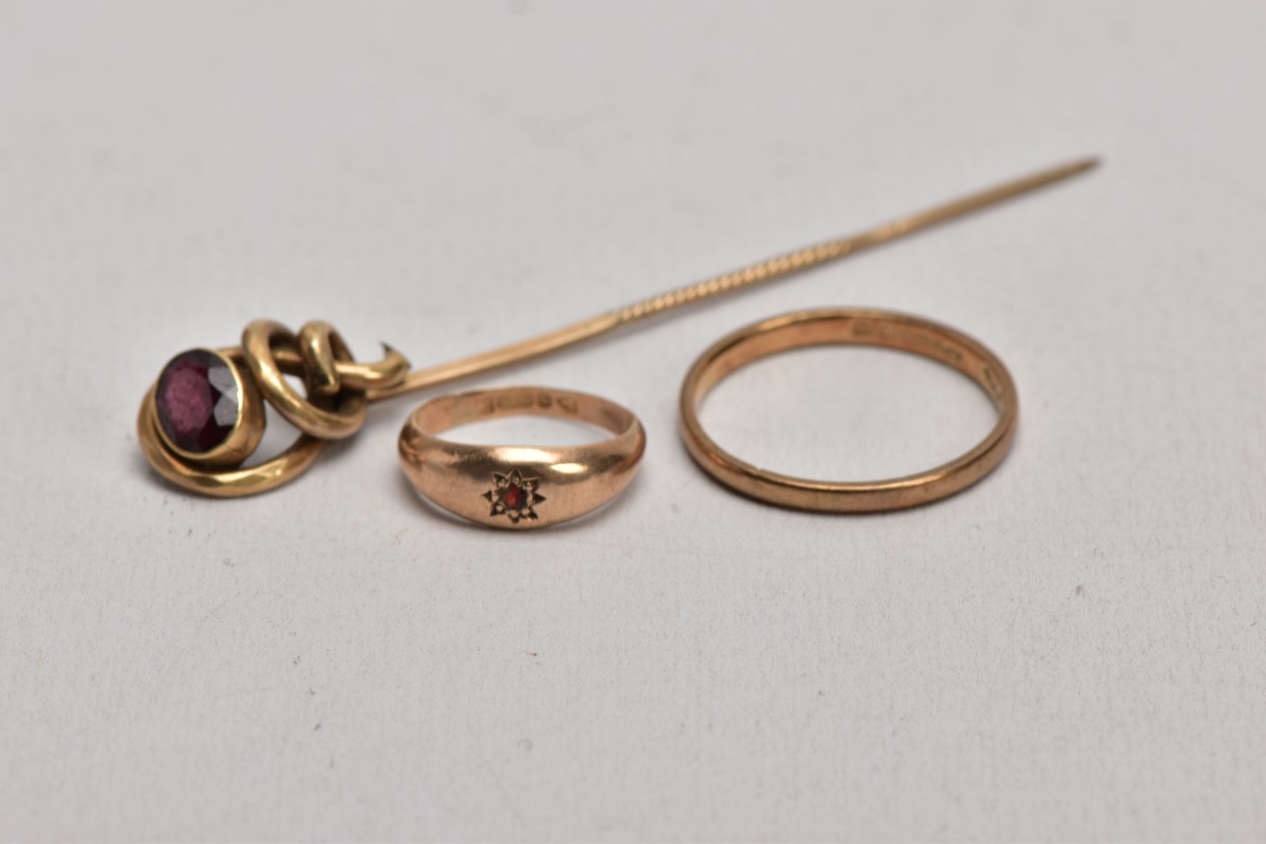 TWO 9CT GOLD RINGS AND A YELLOW METAL GARNET SET STICK PIN, the first a thin plain polished band,