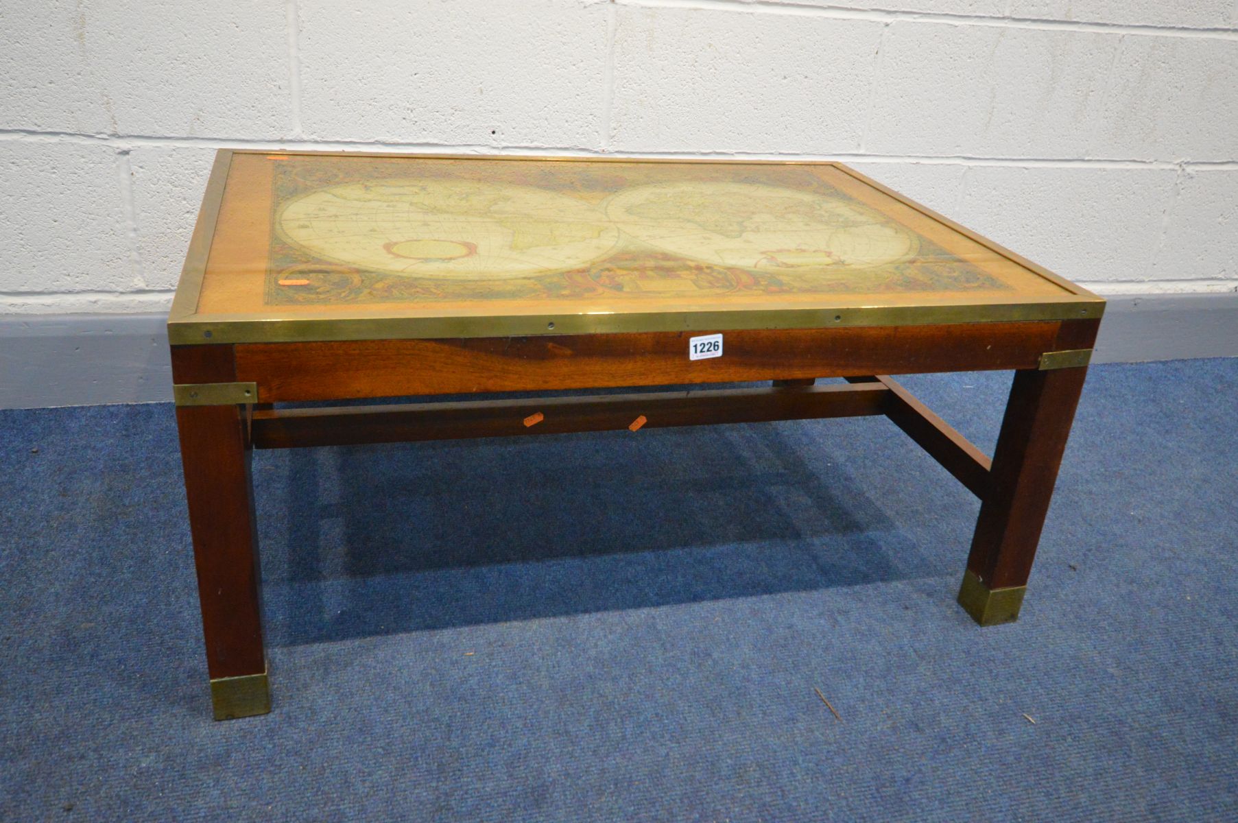 A MAHOGANY AND BRASS BANDED COFFEE TABLE, depicting a world map in two globes, with a glass top