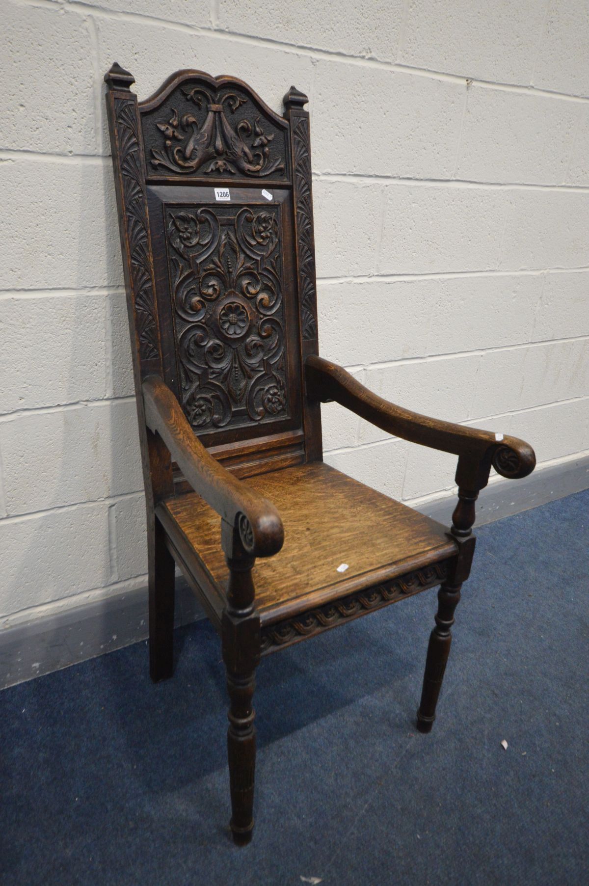 A 19TH CENTURY CARVED OAK WAINSCOT CHAIR, foliate carved back, solid seat and open armrests, width