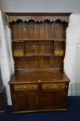 A SOLID OAK DRESSER, the top with a wavy apron, two shelves, above a base with two drawers and