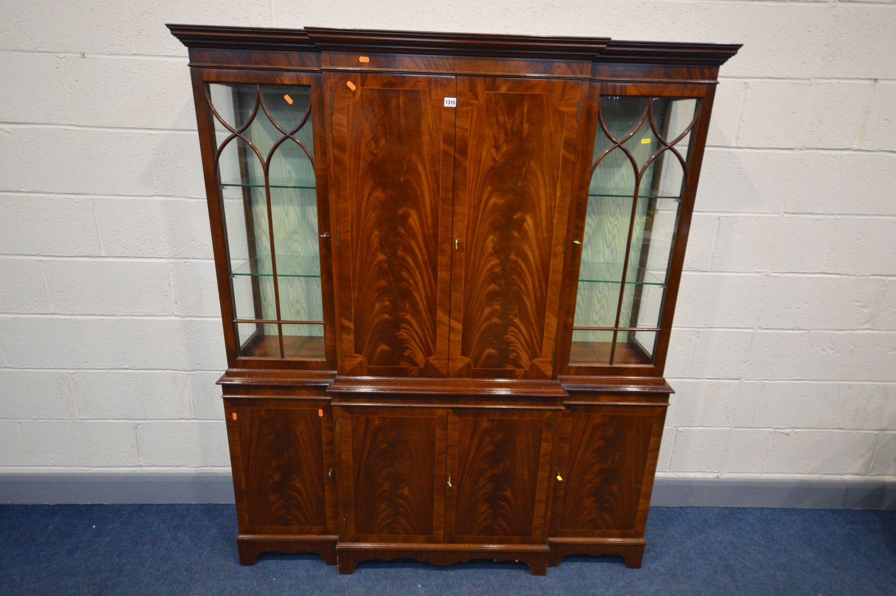 A REPRODUDUCTION MAHOGANY BREAKFRONT BOOKCASE/COCKTAIL CABINET, the top section with two glazed