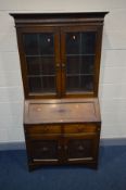 AN EARLY 20TH CENTURY OAK BUREAU BOOKCASE, fixed cornice above double lead glazed doors enclosing