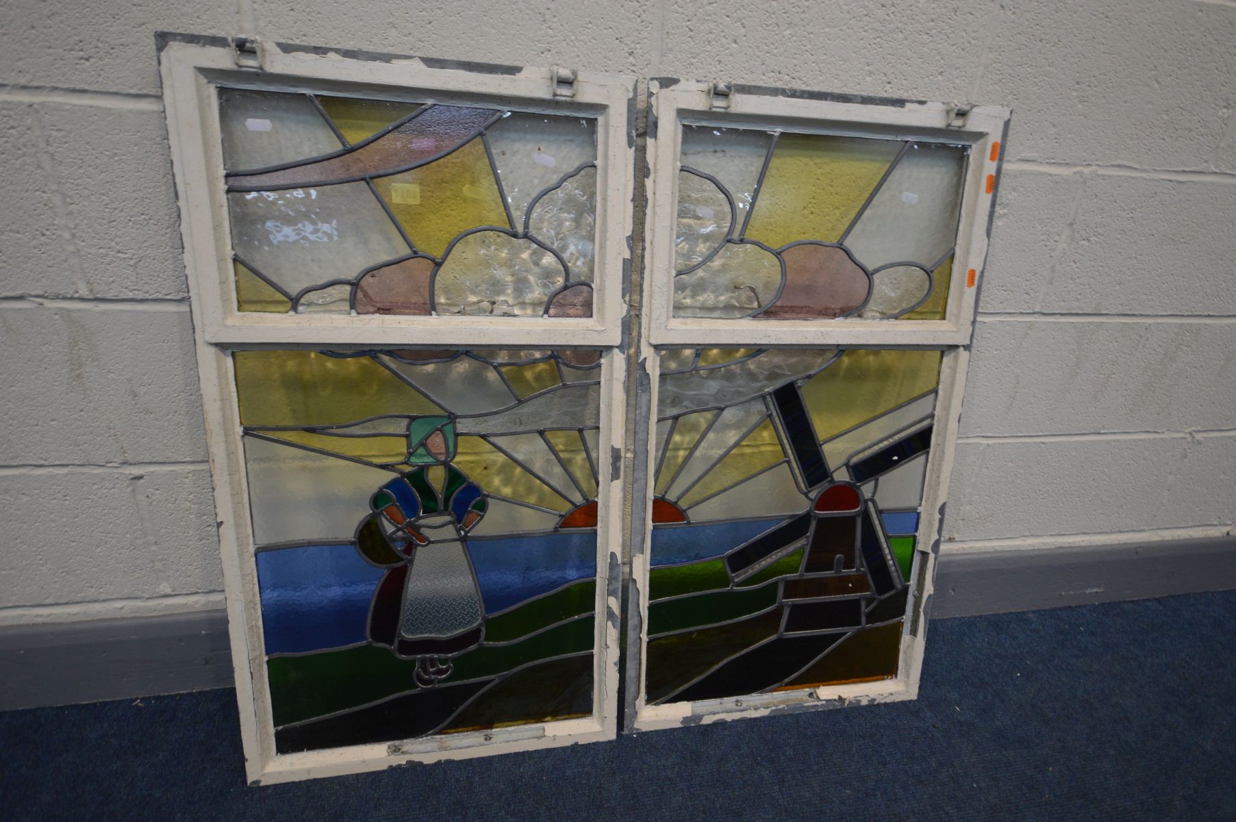 A PAIR OF EARLY 20TH CENTURY STAINED GLASS WINDOWS depicting a Dutch seascape with a windmill,
