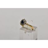 AN 18CT GOLD SAPPHIRE AND DIAMOND CLUSTER RING, centring on an oval cut blue sapphire, within a