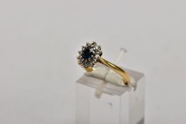 AN 18CT GOLD SAPPHIRE AND DIAMOND CLUSTER RING, centring on an oval cut blue sapphire, within a