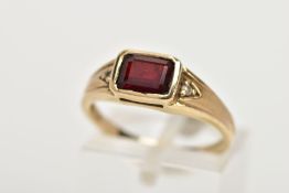 A 9CT GOLD GARNET AND DIAMOND DRESS RING, centring on a rectangular cut garnet, flanked with round