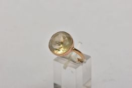 A YELLOW METAL CITRINE DRESS RING, set with a circular cut citrine within a collet mount, plain