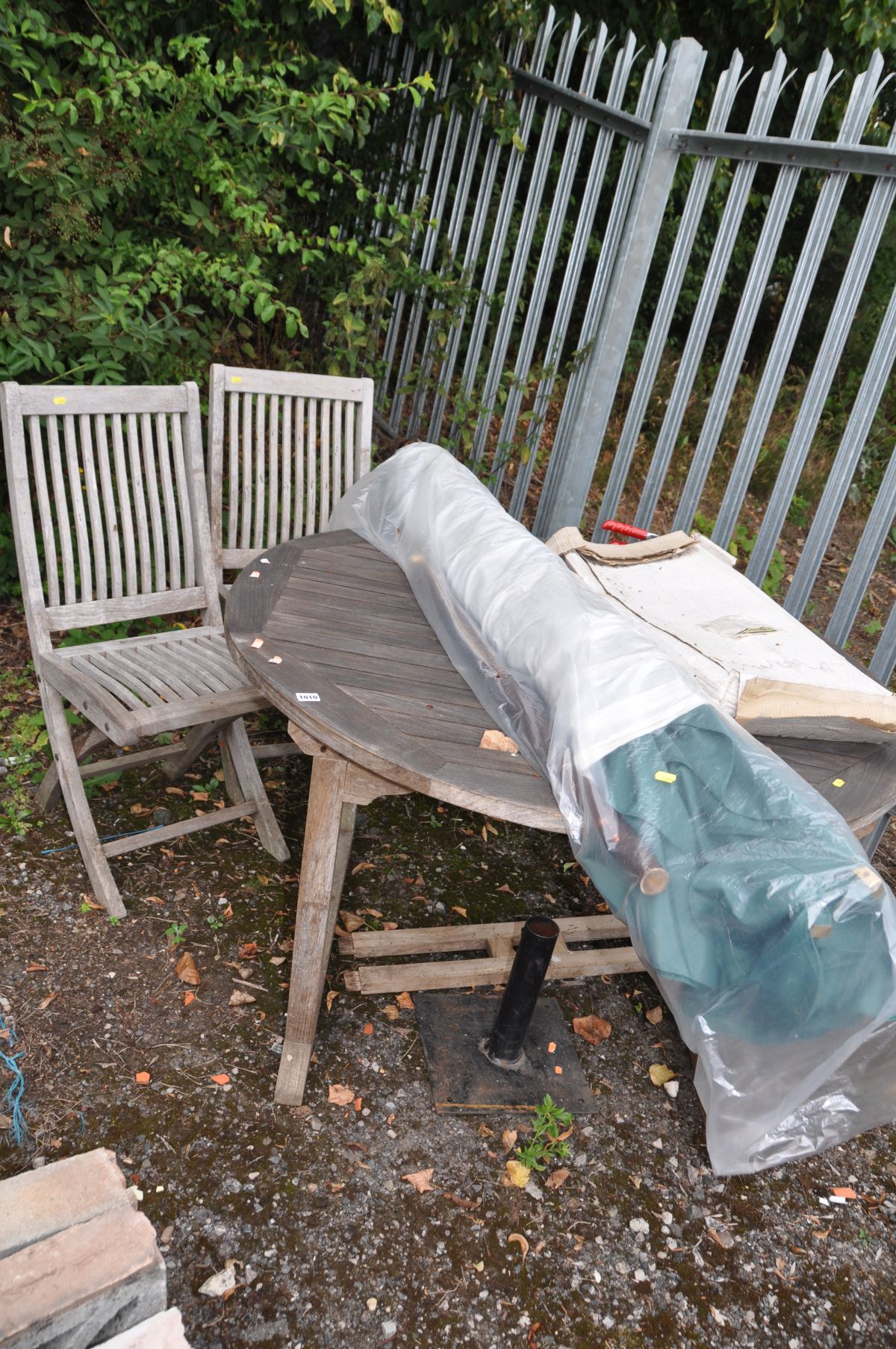 A MODERN HARDWOOD GARDEN TABLE 125cm in diameter (stretcher base dislocated), two folding chairs (