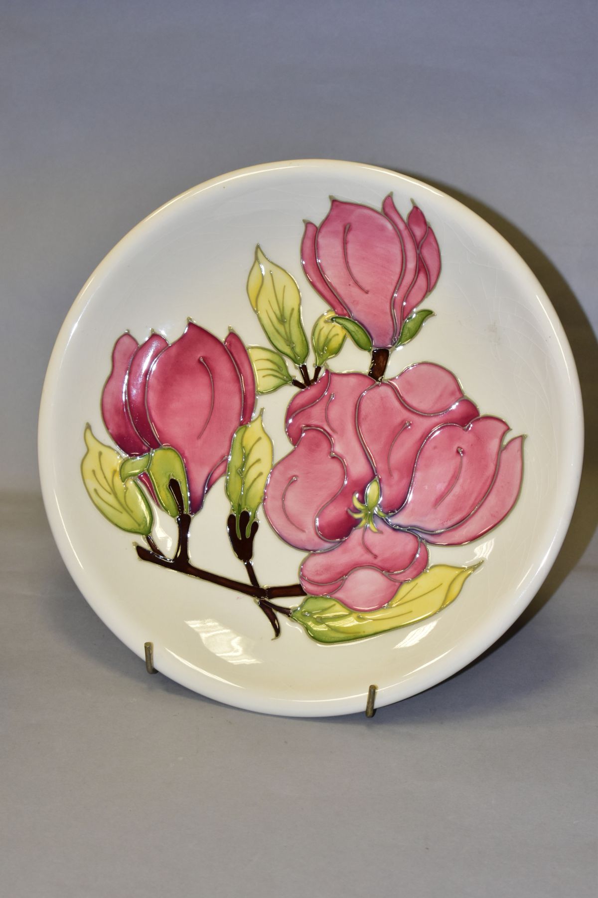 A MOORCROFT POTTERY CHARGER, with pink Magnolia design on cream ground, painted WM and impressed