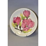 A MOORCROFT POTTERY CHARGER, with pink Magnolia design on cream ground, painted WM and impressed