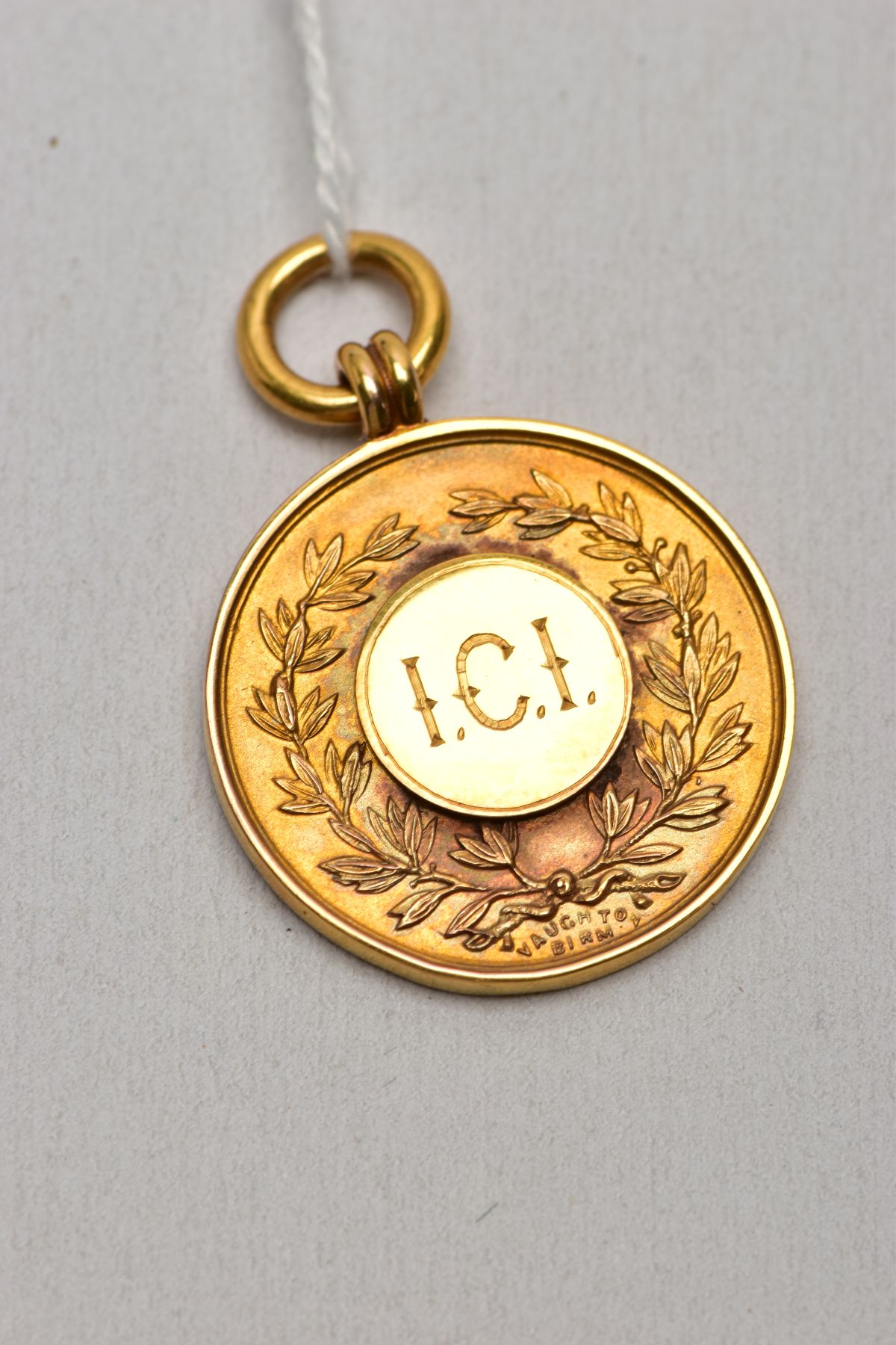 A 9CT GOLD FOB MEDAL, of a circular form, engraved to the front 'I.C.I' within a foliate wreath,