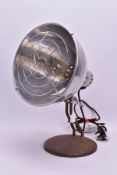 A VINTAGE HEAT LAMP, the converted light fitting within a stainless steel shade, on a circular metal