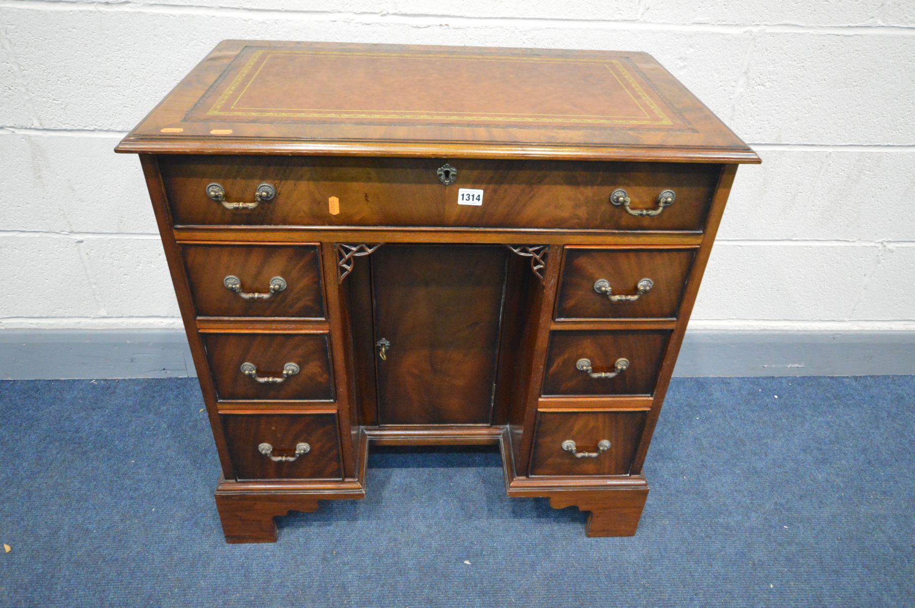 A GOOD REPRODUCTION SLIM MAHOGANY KNEE HOLE DESK, brown and gilt tooled inlay top, seven drawers and