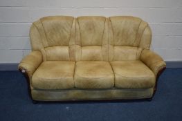 A SMOKEY BEIGE FAUX LEATHER THREE SEATER SETTEE, with a wooden front frame, on bun feet, inner width