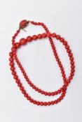 A DYED CORAL BEAD NECKLACE, designed as a row of graduated dyed coral beads measuring