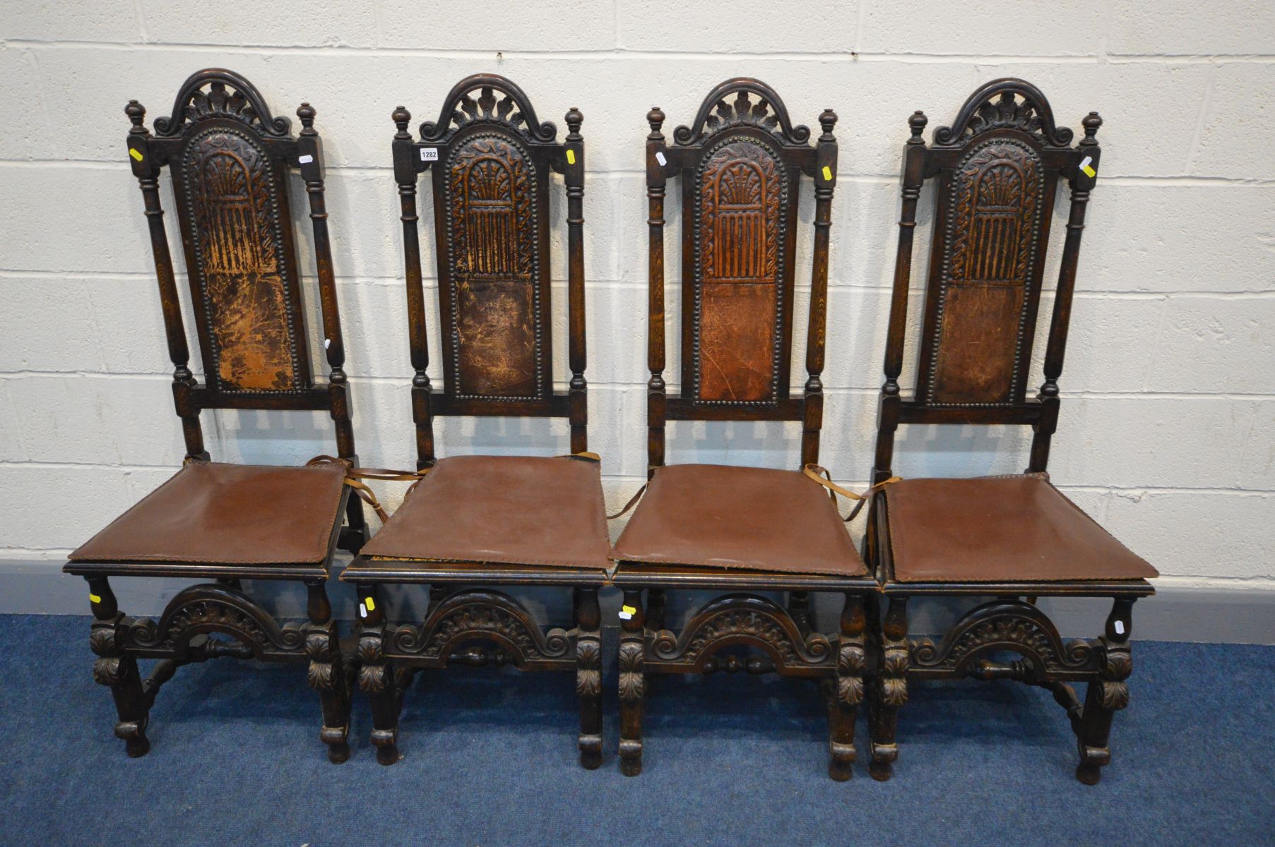 A SET OF FOUR CARVED OAK BAROQUE STYLE CHAIRS with embossed leather back and bergère seat, with